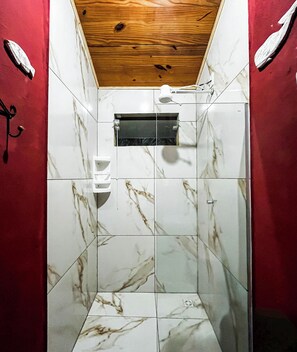 A bathroom with a wooden ceiling, white marble tiles, and a shower area. - Studio apartment in Paraty Mirim, 10 minutes from the beach. (Paraty-Mirim)