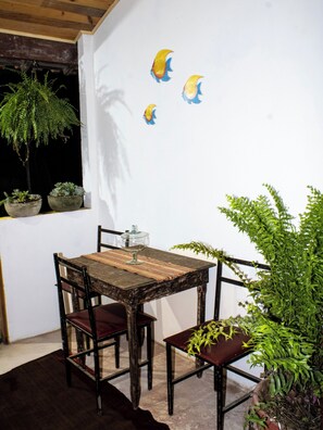 A dining area with a wooden table and chairs, a potted plant, and wall art. - Studio apartment in Paraty Mirim, 10 minutes from the beach. (Paraty-Mirim)
