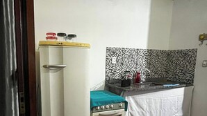 Cozinha compacta com geladeira, fogão e painel de azulejos.