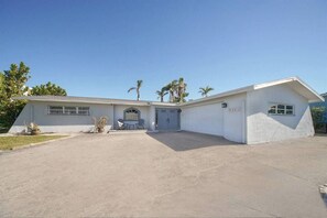 A single-story house with a garage, a covered entryway, and a small porch with two chairs. - Waterfront Cape Coral Oasis: Heated Pool, Spa, Direct Gulf Access & Dock (Cape Coral)