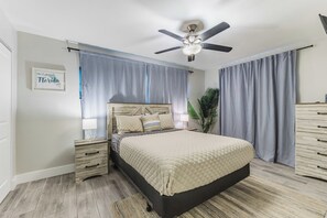 A bedroom with a bed, nightstands, a ceiling fan, and a large window with curtains. - Waterfront Cape Coral Oasis: Heated Pool, Spa, Direct Gulf Access & Dock (Cape Coral)