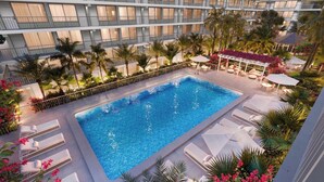 A hotel with a swimming pool, lounge chairs, palm trees, and a covered seating area. - 8 mins to Disney Resort Style Living with Pool (Kissimmee)