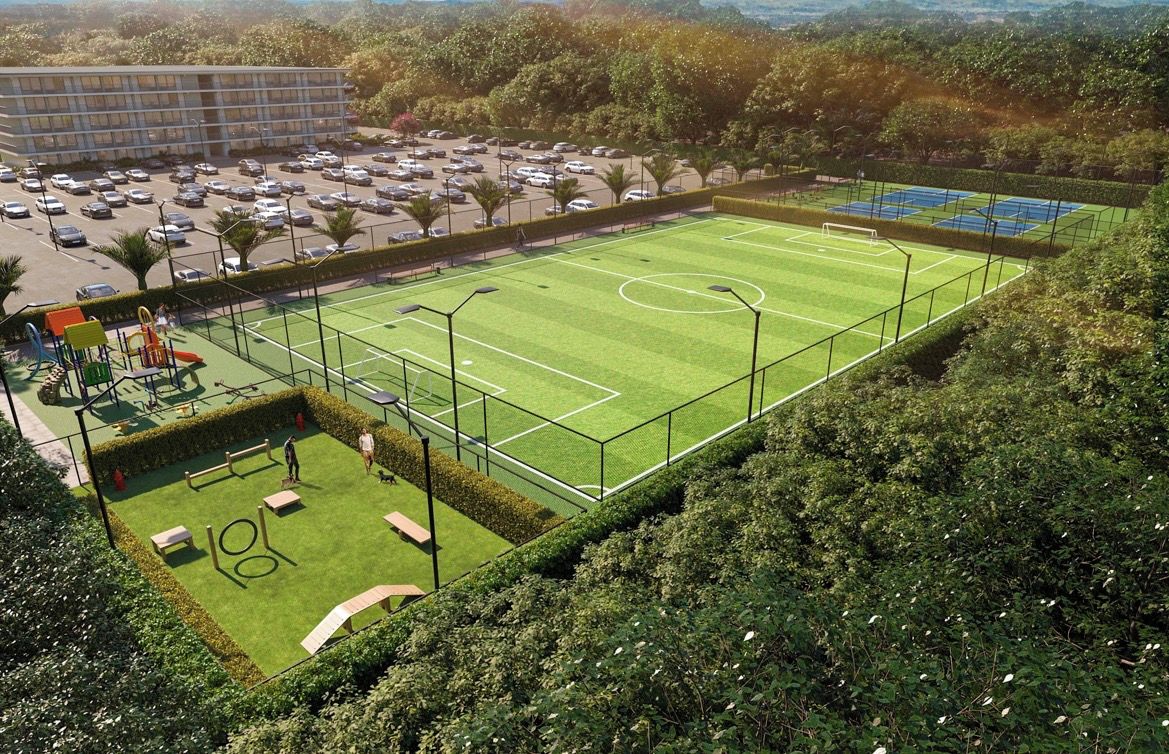 Un complejo deportivo con campo de fútbol, canchas de tenis y estacionamiento.