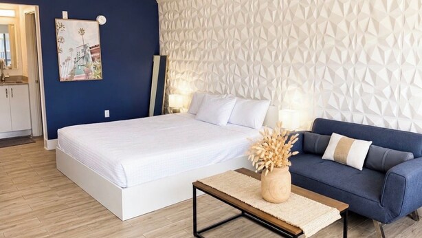 A bedroom with a bed, a sofa, a coffee table, and a wall with a geometric pattern. - 8 mins to Disney Resort Style Living with Pool (Kissimmee)