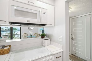 A kitchen with a stove, microwave, and a view of a body of water.