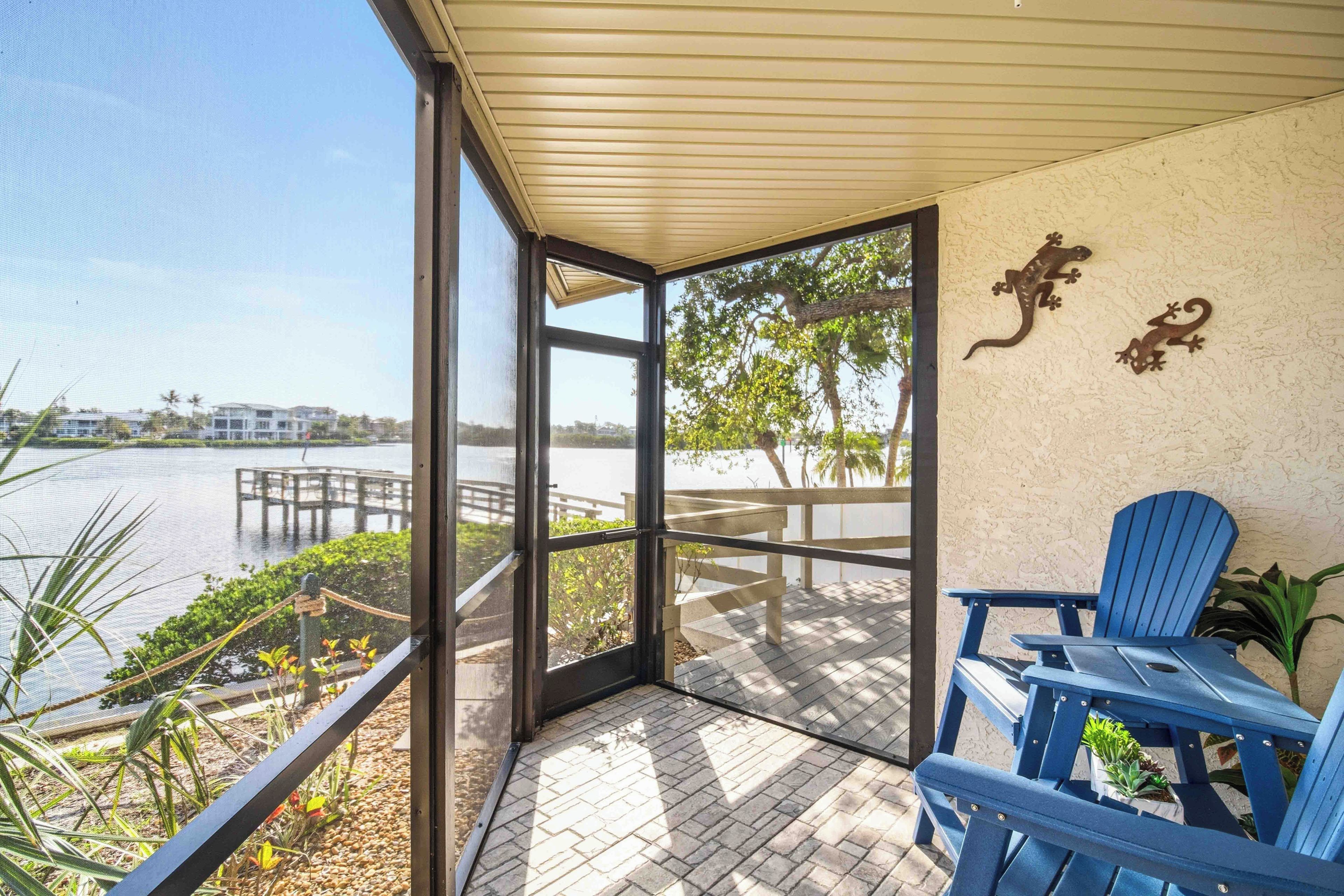 Un espacio al aire libre techado con vista a un lago, un muelle y una silla.