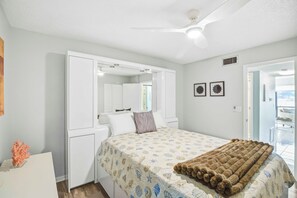 A bedroom with a bed, a wardrobe, a mirror, and a window.