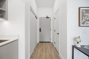 Ein Flur mit Holzboden, weißen Wänden und einer Tür am Ende.