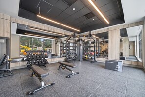 Ein modernes Fitnessstudio mit Kraftgeräten, Bänken und verschiedenen Trainingsbällen.