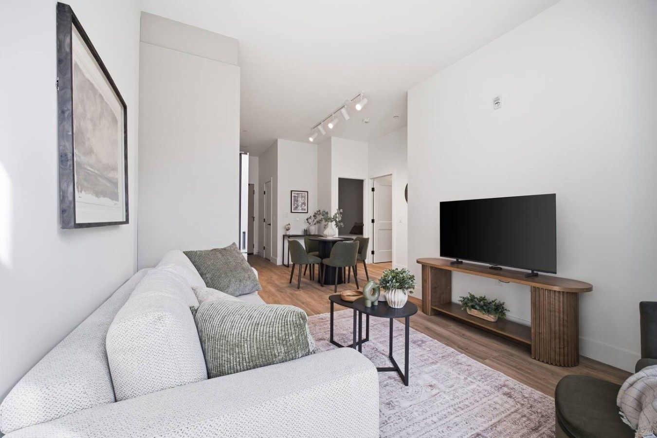 Ein modernes Wohnzimmer mit einer Couch, einem Couchtisch und einem Flachbildfernseher.