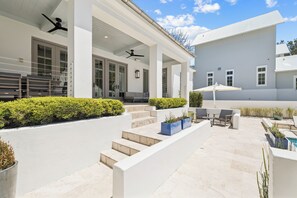 A modern outdoor patio area with steps leading to a covered seating area, outdoor furniture, and potted plants. - Seagrove: Private Heated Pool, Casita Incl, Bikes, 3 min walk to Beach (Seagrove Beach)