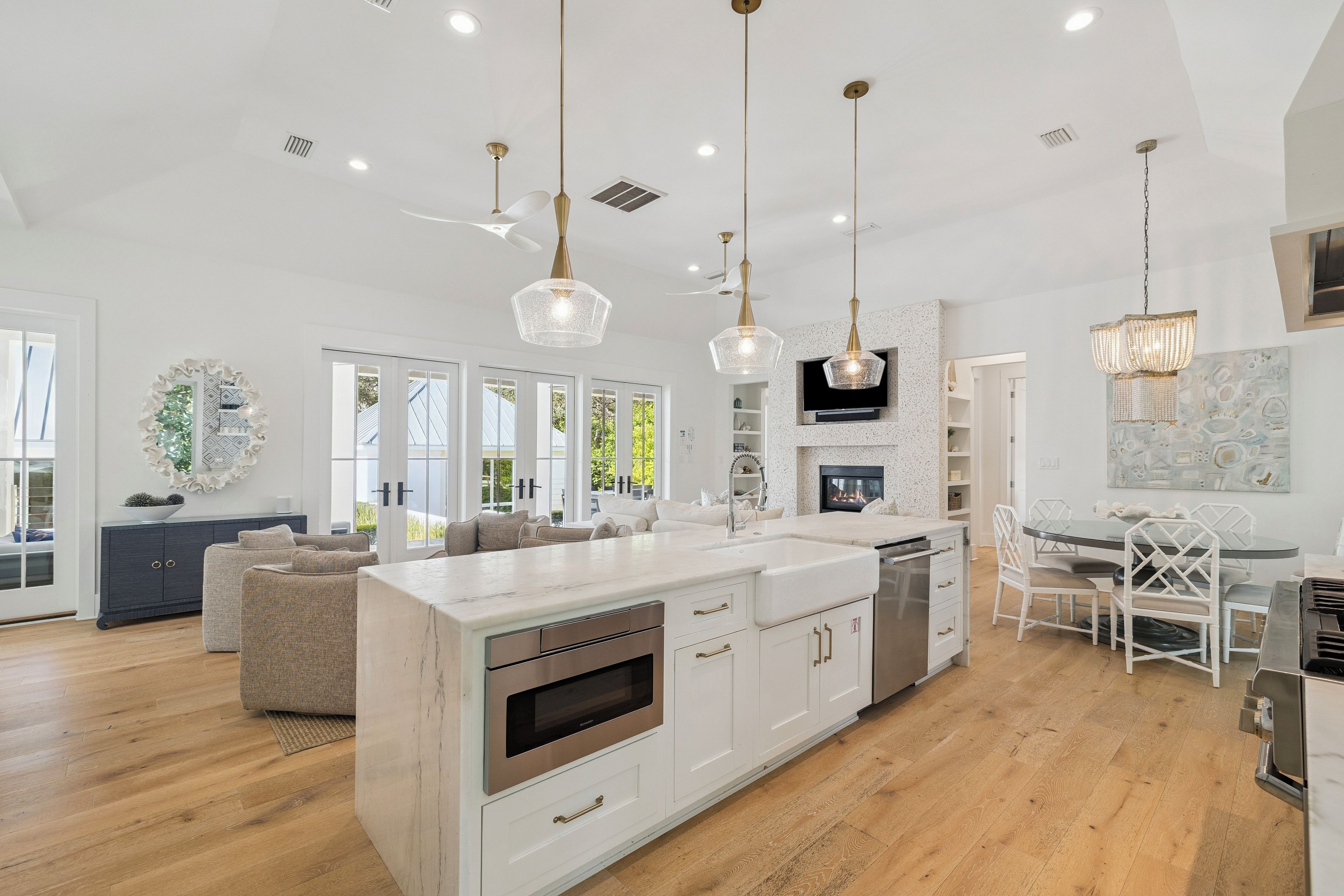 A modern kitchen with a central island, pendant lighting, and a dining area with a glass table.