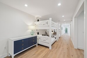 Een modern interieur met een witte console, een stapelbed en een gang naar een deur.
