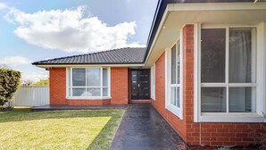 A single-story house with a brick exterior, a front door, and a small front yard with grass and a pathway leading to the door. - The Apex, Pet-Friendly Dubbo Home (Dubbo)