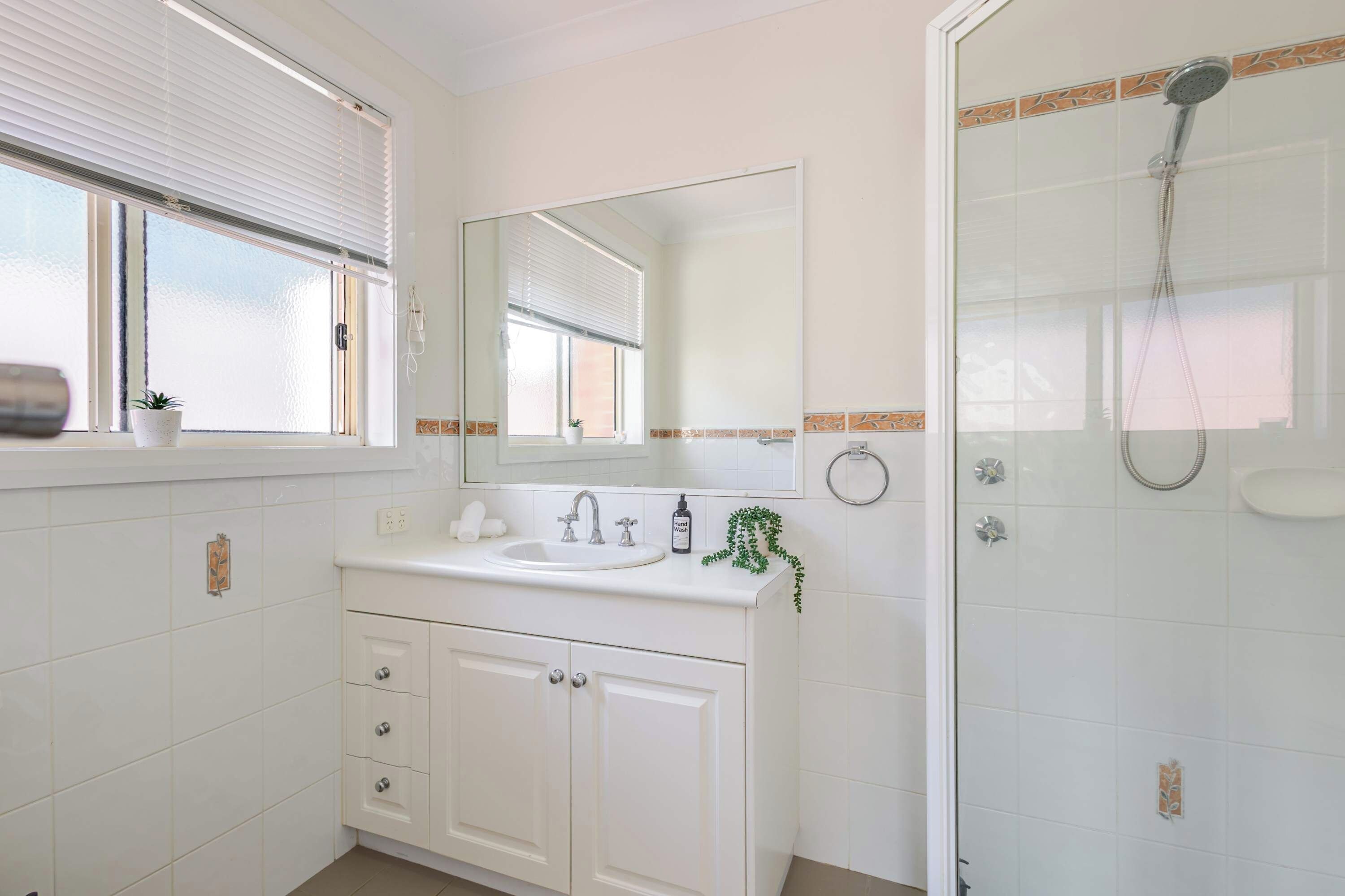 A bathroom with a sink, mirror, and shower.