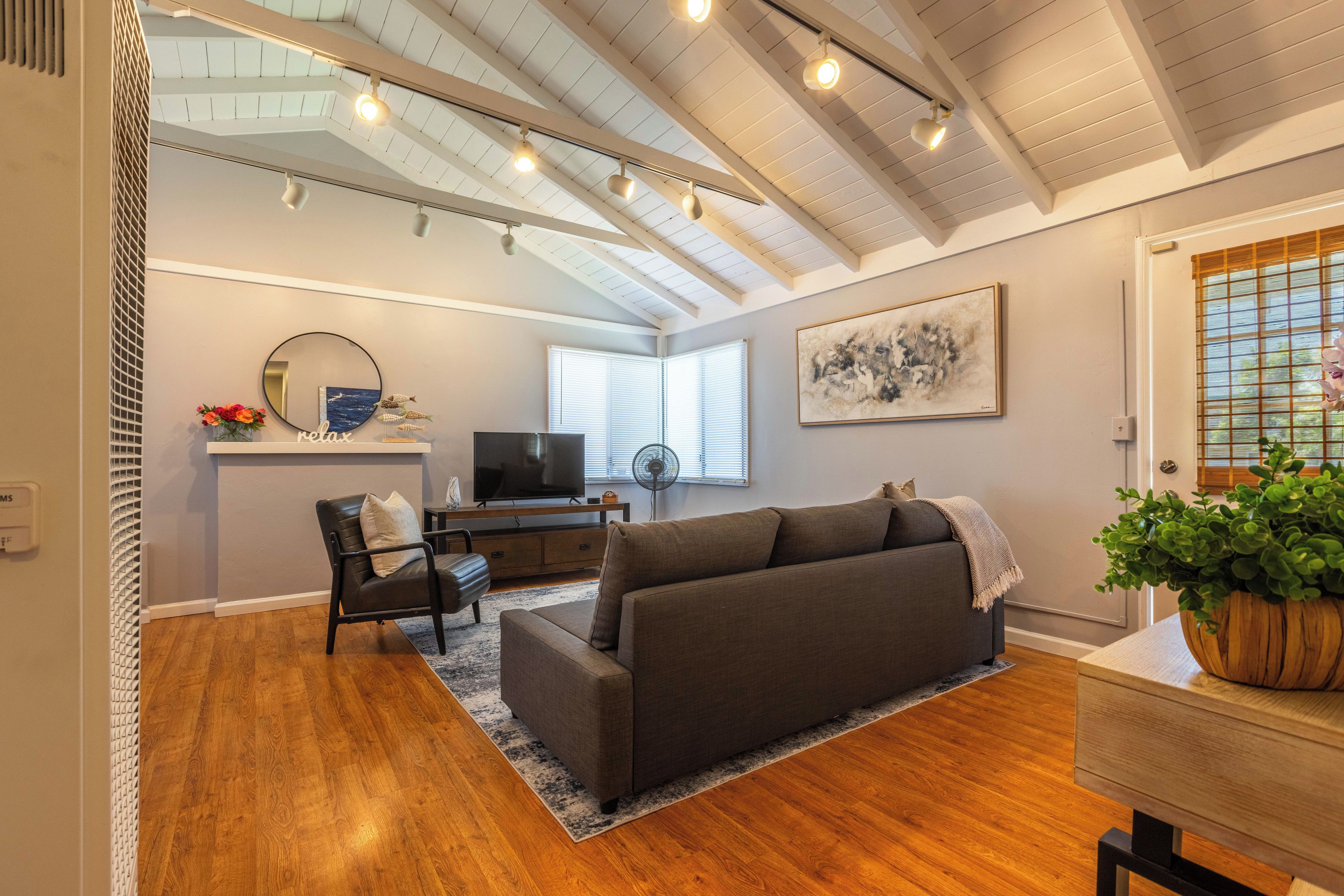 A modern living room with a sofa, a television, and a desk.