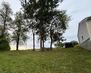 A grassy yard with trees and a parked truck. - Get the break you deserve, at the River Respite. (Memphis)
