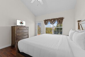 A bedroom with a bed, a dresser, a window with curtains, and a ceiling fan. - Stay in the Heart of Branson • Gated 3BR Townhome • Pool • Near Shows, Shopping & Golf (Branson)