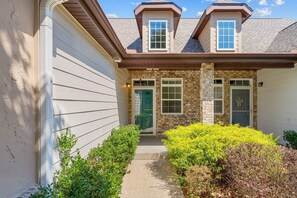 A two-story house with a front porch, a brick chimney, and a green door. - Stay in the Heart of Branson • Gated 3BR Townhome • Pool • Near Shows, Shopping & Golf (Branson)
