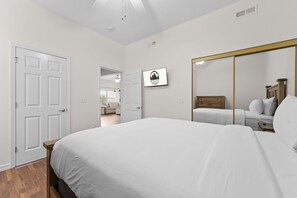 Une chambre à coucher comprenant un lit, une commode, un miroir et une porte donnant sur une autre pièce.