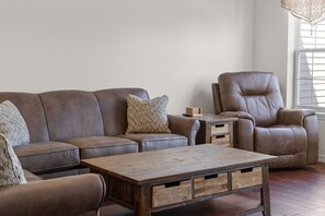 A living room with a brown leather sofa, a matching leather armchair, a wooden coffee table, and a small wooden side table with drawers. - Stay in the Heart of Branson • Gated 3BR Townhome • Pool • Near Shows, Shopping & Golf (Branson)