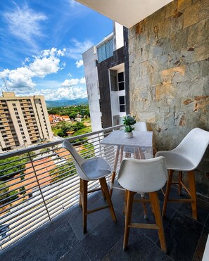 A balcony with a table and chairs, overlooking a cityscape with buildings and greenery. - Lujo&Exclusividad, Bello Apto con Planta Eléctrica (Barquisimeto)
