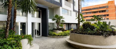 A modern building with a courtyard featuring palm trees and planters.