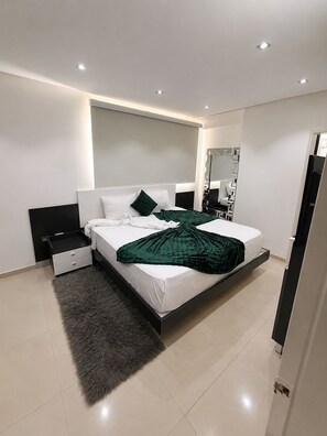 A modern bedroom with a bed, nightstands, a mirror, and a fluffy rug. - Lujo&Exclusividad, Bello Apto con Planta Eléctrica (Barquisimeto)