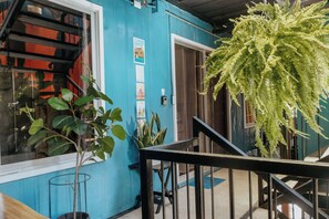 Un bâtiment bleu avec un escalier, une plante en pot et une fenêtre qui reflète la lumière.