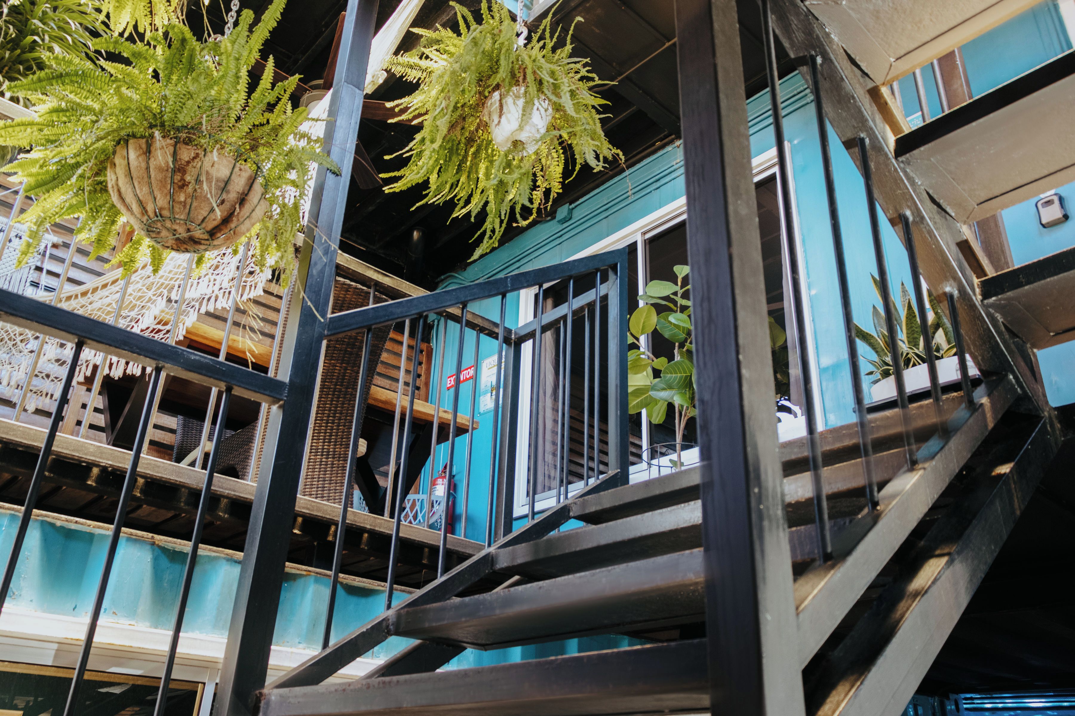 A multi-level building with outdoor terraces, metal railings, and hanging planters.