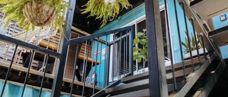 Un edificio de varios niveles con terrazas exteriores, barandillas metálicas y jardineras colgantes.