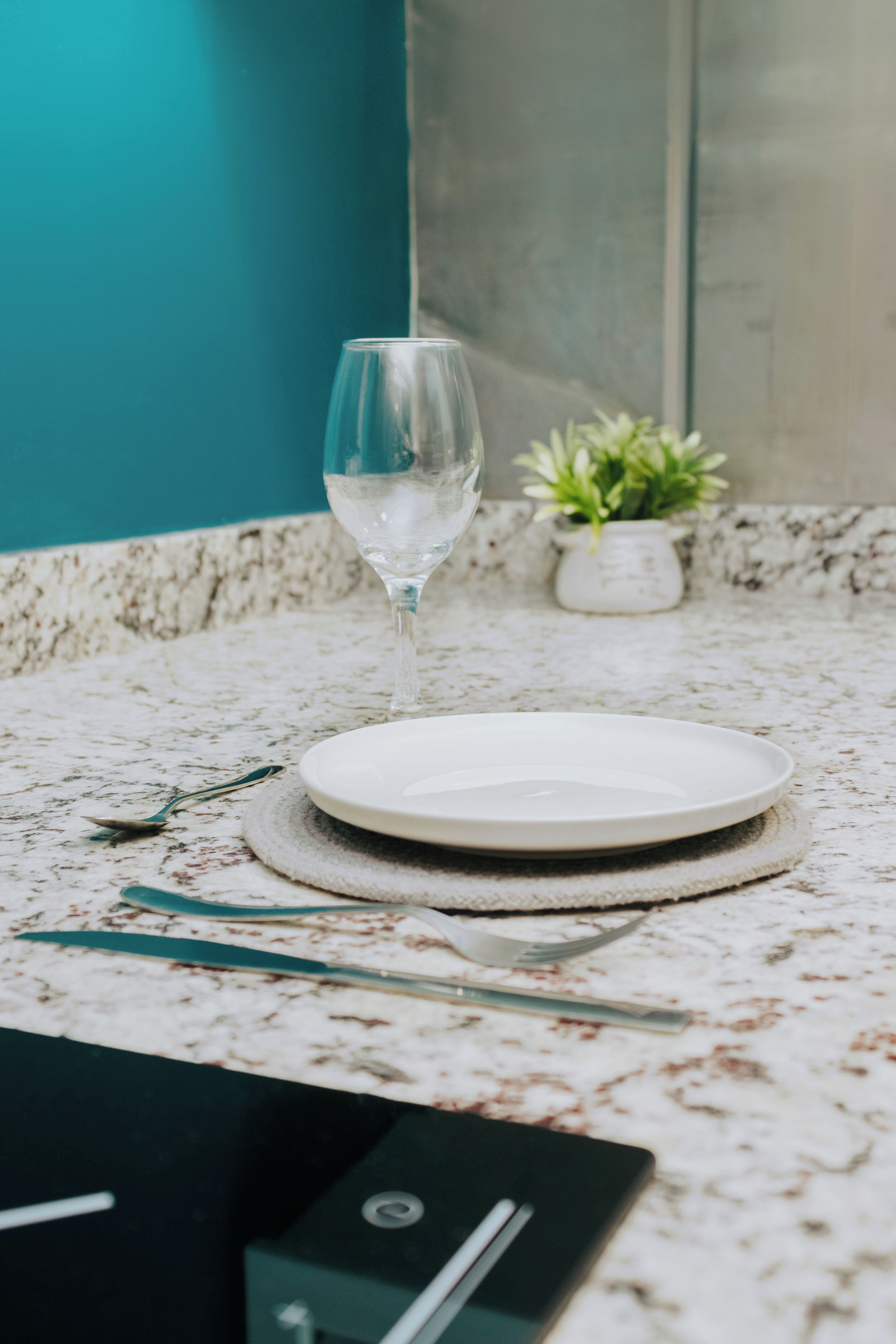 A clean, modern bathroom with a marble countertop, a glass of water, a plate, and a small potted plant.