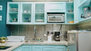 A kitchen with teal cabinets, a stainless steel sink, and a built-in toaster oven.
