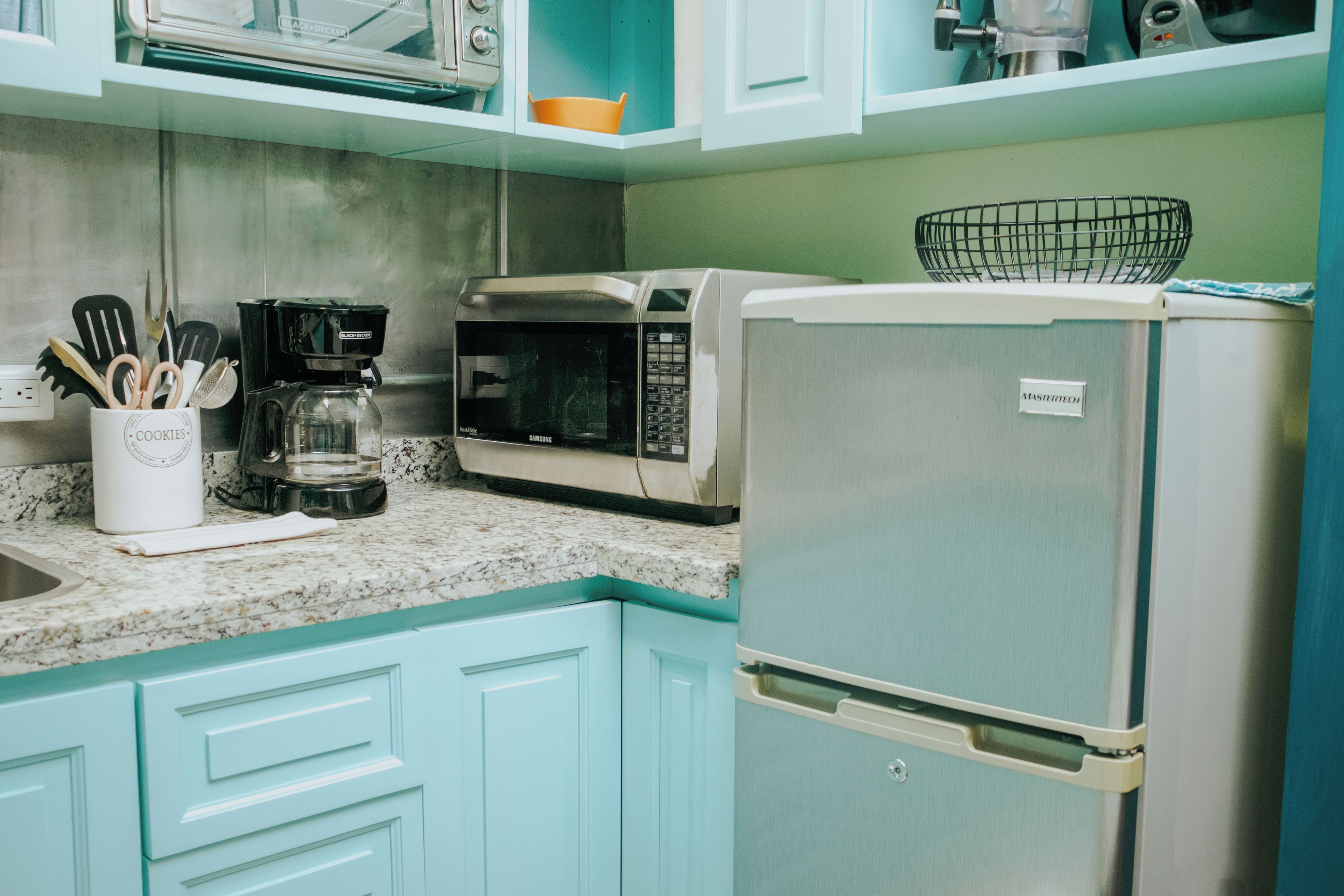 Una cucina dotata di forno a microonde, macchina del caffè e frigorifero.
