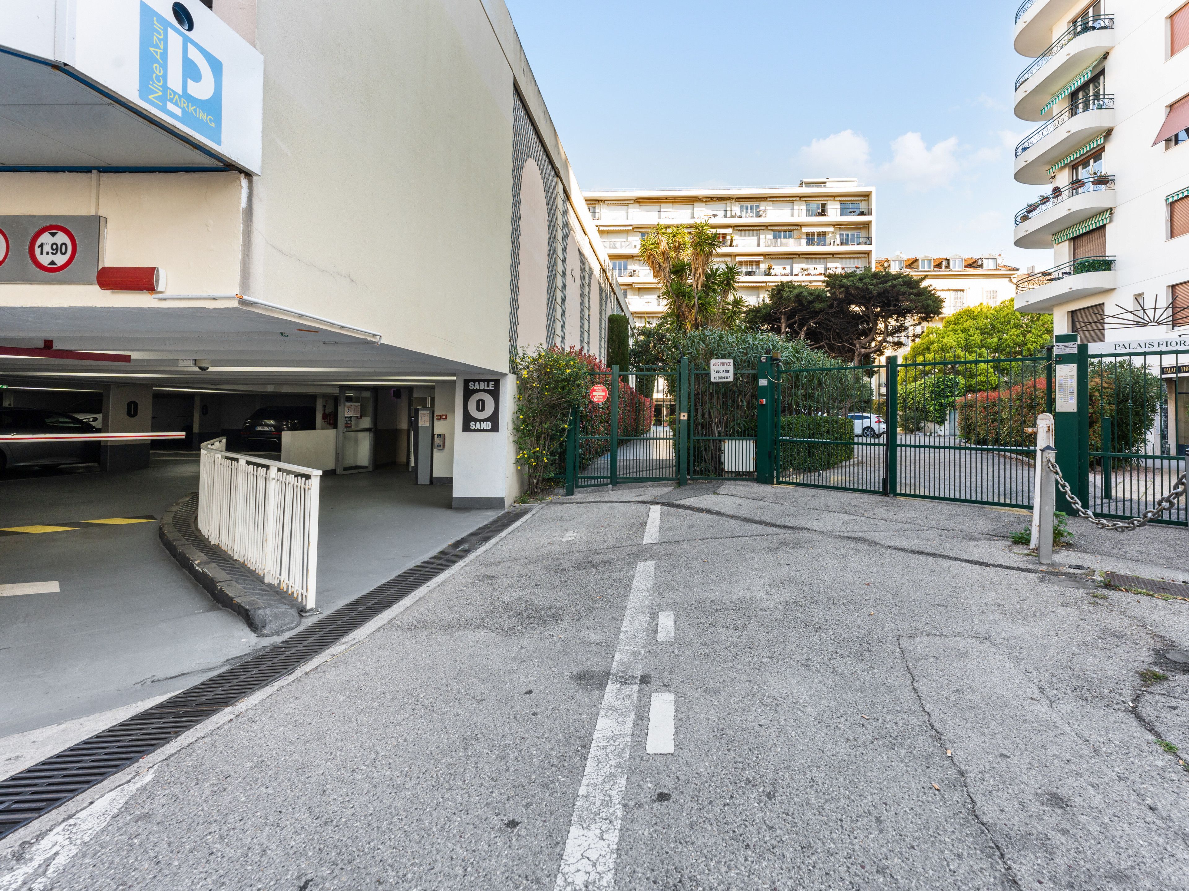 A parking garage entrance with a sign for 'Nice Azure Parking' and a 'Sable 0 Sand' sign.