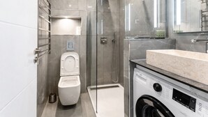Ein modernes Badezimmer mit einer Duschkabine, einer Toilette und einer Waschmaschine.
