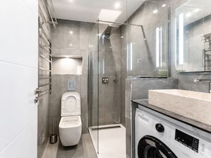 Ein modernes Badezimmer mit einer Duschkabine, einer Toilette und einer Waschmaschine.