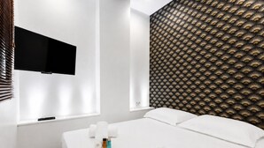 Ein Hotelzimmer mit einem Bett, einem flachbildfernseher an der Wand und einer Wandverkleidung mit Muster.