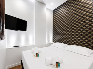 Ein Hotelzimmer mit einem Bett, einem flachbildfernseher an der Wand und einer Wandverkleidung mit Muster.