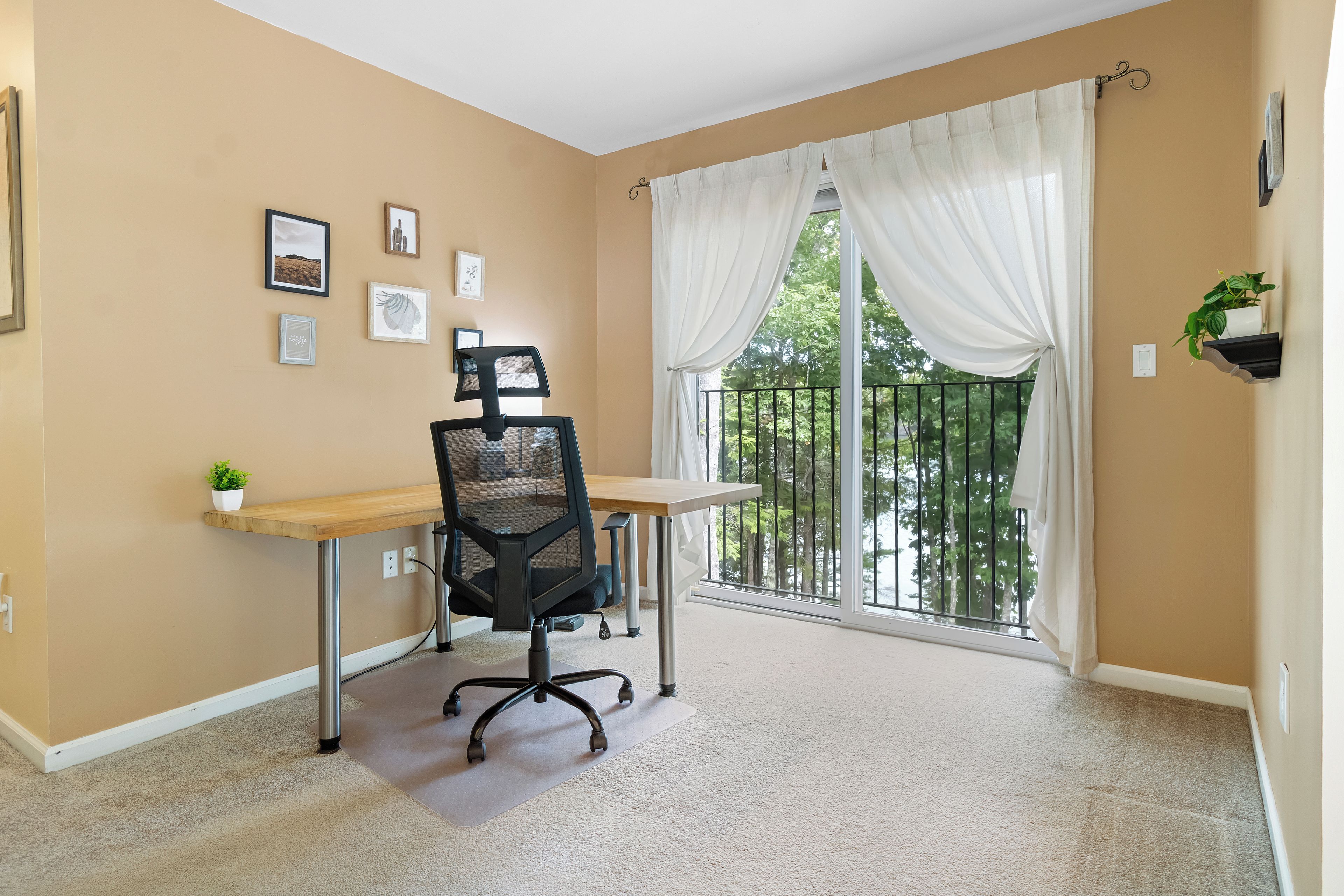 Une pièce comprenant un bureau, une chaise et une grande fenêtre avec des rideaux.