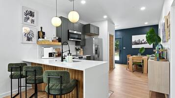 A modern kitchen with a central island, bar stools, and a dining area with a table and chairs.