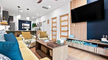 A modern living room with a sofa, coffee table, and a TV mounted on the wall.