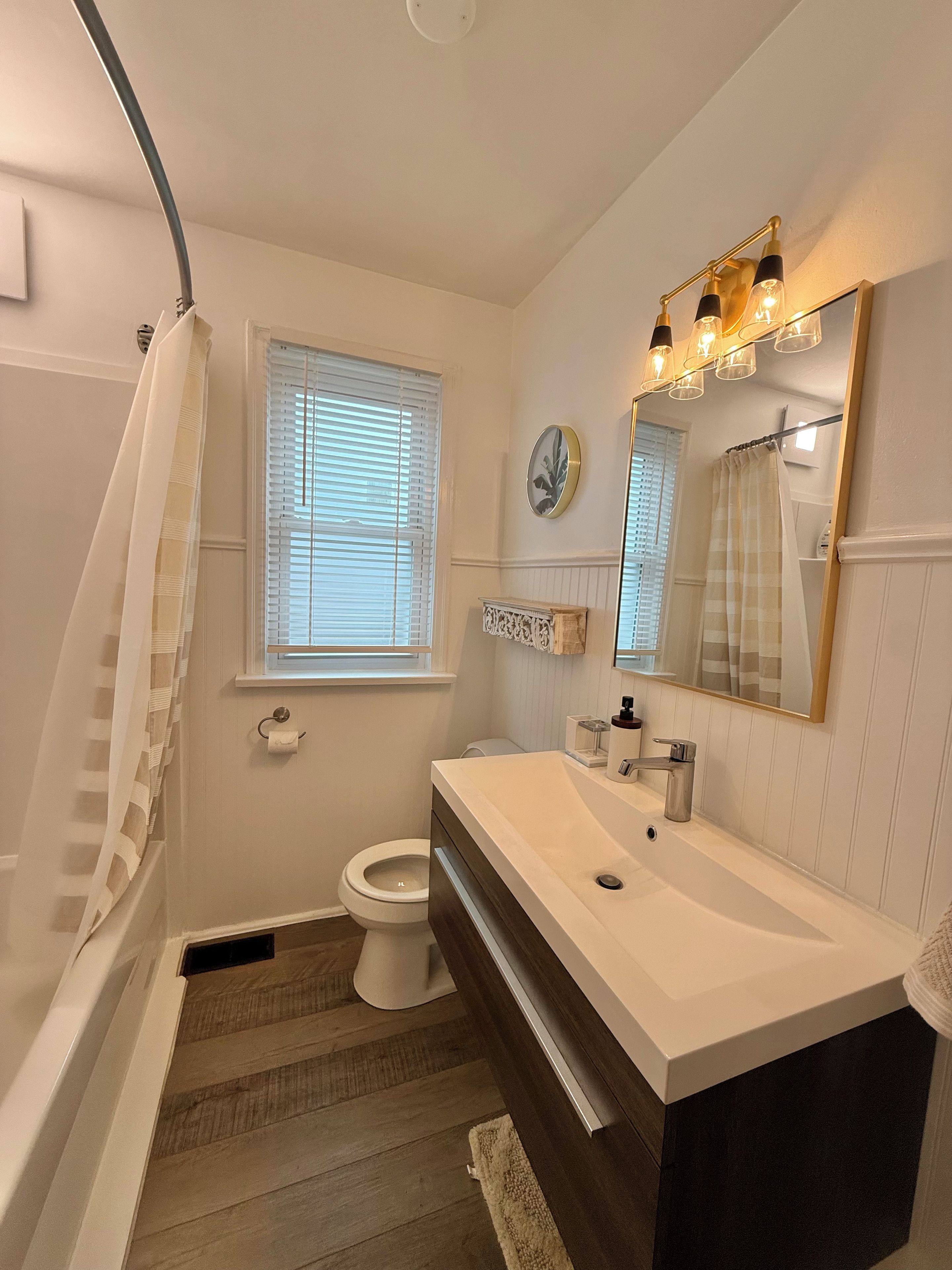 Une salle de bain comprenant une baignoire, des toilettes, un meuble-lavabo et un miroir.