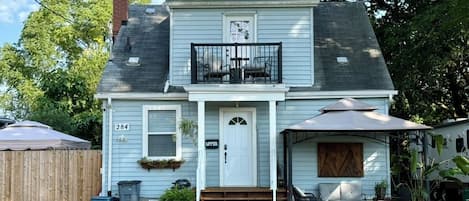 Une maison à deux étages avec un porche à l’avant, un petit balcon et le numéro « 284 » sur la porte.