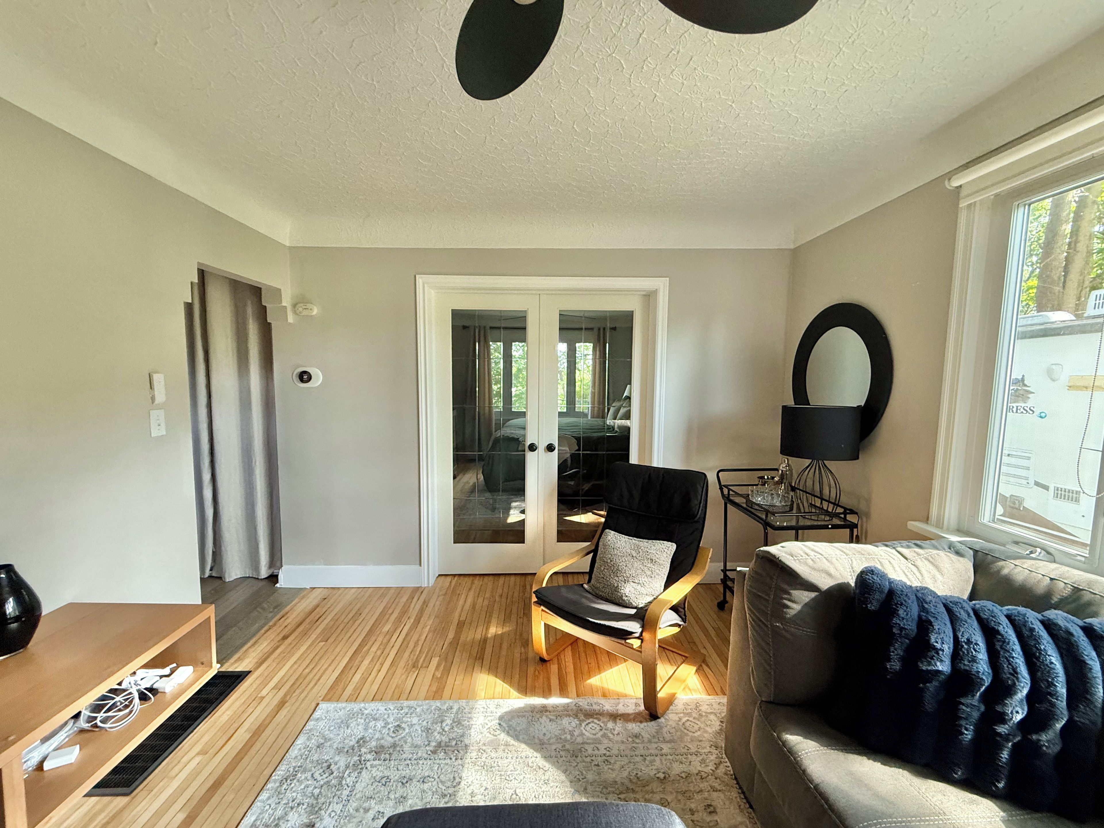 Een woonkamer met een bank, een fauteuil, een salontafel en een raam met uitzicht.