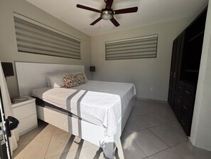 A bedroom with a bed, a nightstand, a ceiling fan, and a wardrobe. - Tropical Escape 3 BR Private Pool / lawn / Fenced (Sosua)