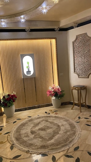 A room with a patterned carpet, a wooden panel wall, a decorative mirror, and two potted plants. - Near the pyramids and the new Grand Egyptian Museum! (Pyramids garden)