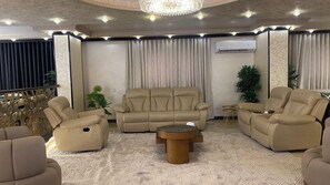 A living room with a sofa, armchairs, a coffee table, and decorative plants.