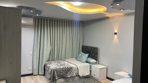 A modern bedroom with a bed, nightstands, and a ceiling light fixture. - Near the pyramids and the new Grand Egyptian Museum! (Pyramids garden)
