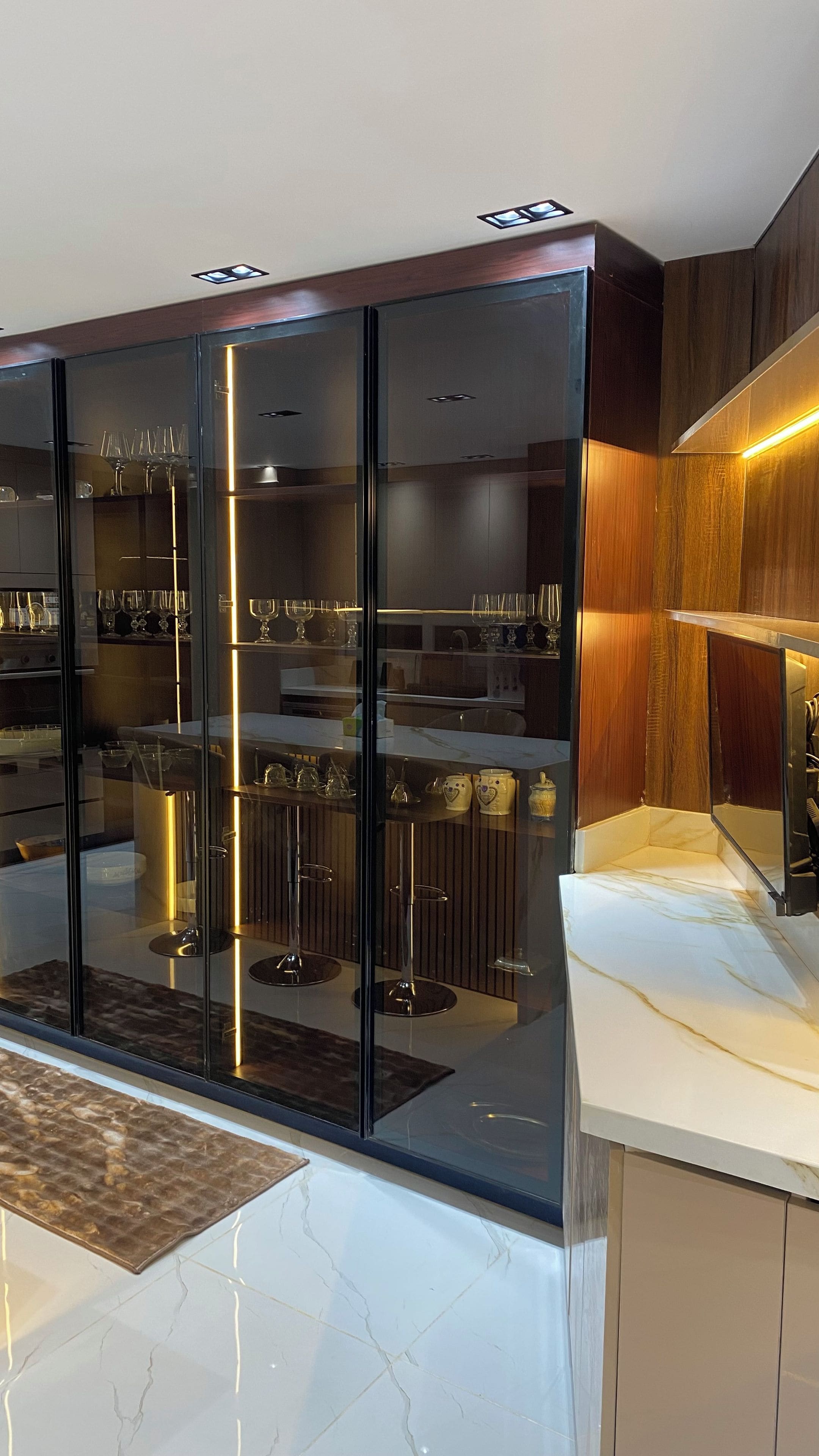 A modern kitchen with a glass-fronted cabinet, stainless steel appliances, and a marble countertop.